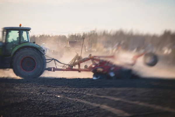 ディスクの収穫システムを持つトラクターは 耕作された農場を耕し 土壌を耕し 準備するプロセス 日没時に畑で作物を播種するトラクター 農業コンセプト 機械を耕します — ストック写真