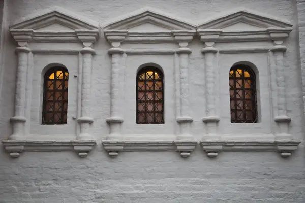 Three windows in a white stone wall