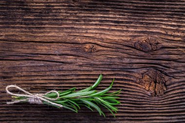 Eski ahşap masada taze kokulu biberiye dalı.