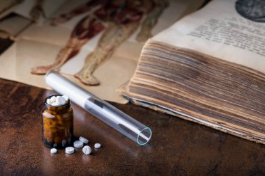 Cam ampullü beyaz haplar ve eski tıp kitapları.