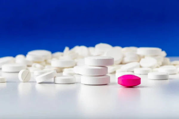 Bir sürü beyaz tablet. Dağınık haplar. Tek pembe hap.