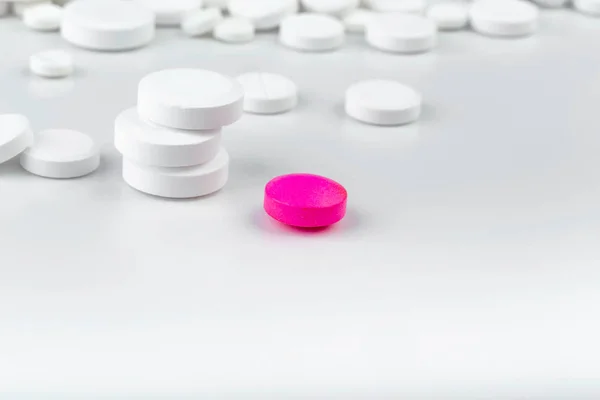 Bunch of white tablets. Scattered pills. Single pink pill — Stock Photo, Image