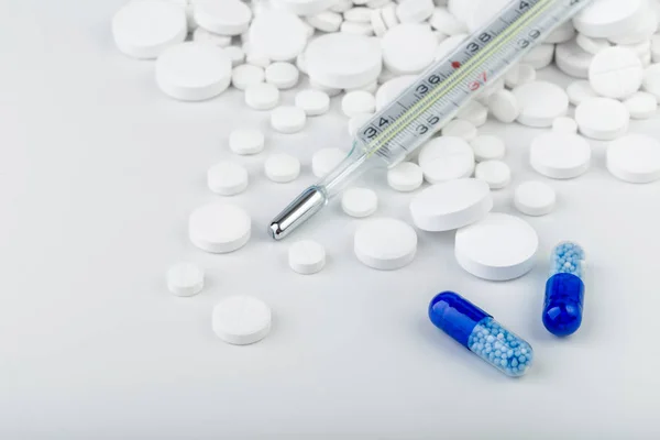 Manojo de comprimidos blancos con pastillas azules y termómetro . — Foto de Stock