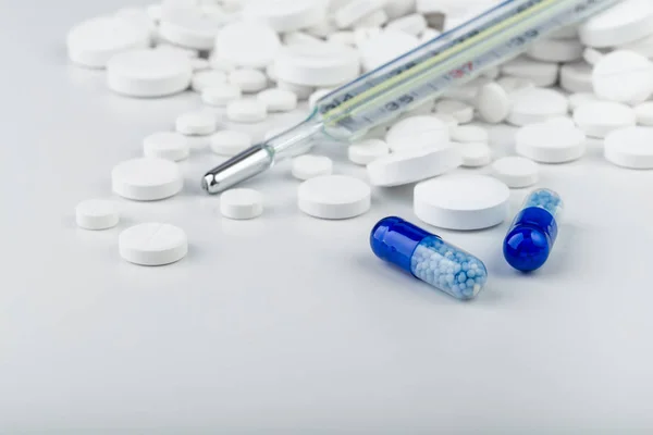 Manojo de comprimidos blancos con pastillas azules y termómetro . — Foto de Stock