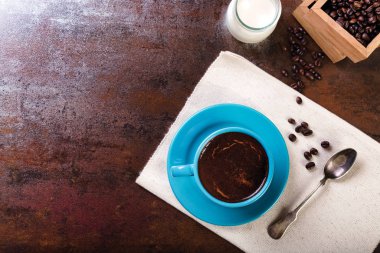 Bir fincan kahve ve içi kahve dolu ahşap kaplar.