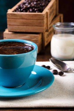 Bir fincan kahve ve içi kahve dolu ahşap kaplar.