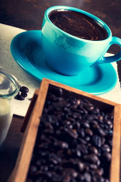 Taza de café y contenedores de madera llenos de granos de cofee — Foto de Stock