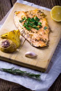 Trout with potateos on wooden board.