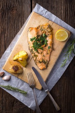 Trout with potateos on wooden board.