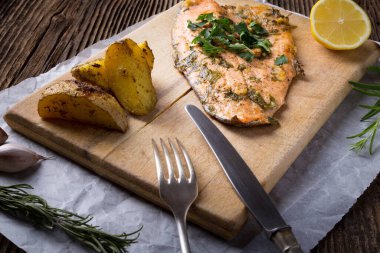 Trout with potateos on wooden board.