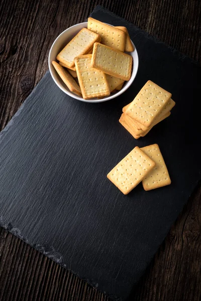 Dry salted crackers in a bowl on granite plate — Stock Photo, Image