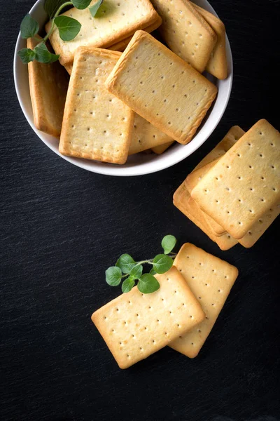 Dry salted crackers on granite plate with oregano — Stock Photo, Image