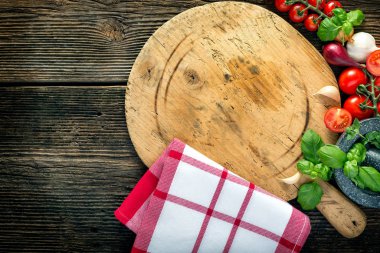 Tahtada sebzeler, otlar ve taş öğütücü var.