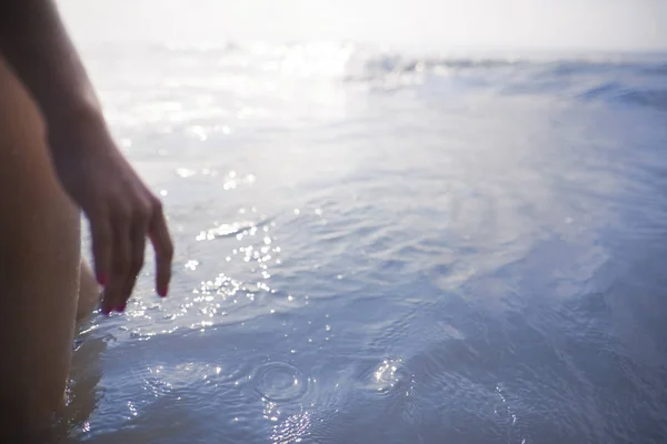 女人的腿和手正站着海洋 — 图库照片