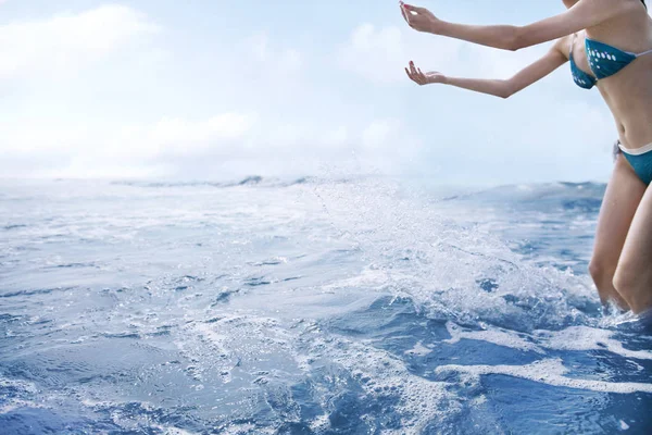Vrouw werpen van water in lucht bij het strand — Stockfoto
