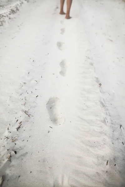 Person som lämnar fotspår i sanden på stranden — Stockfoto