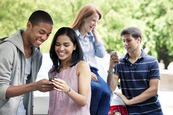 Adolescenti che utilizzano telefoni cellulari vicino all'auto — Foto Stock