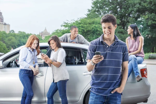 Tonåringar använder mobiltelefoner nära bil — Stockfoto