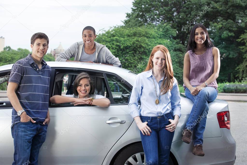 Happy teenagers posing near car