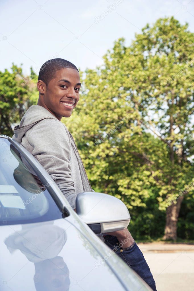 Teenage boy standing near car