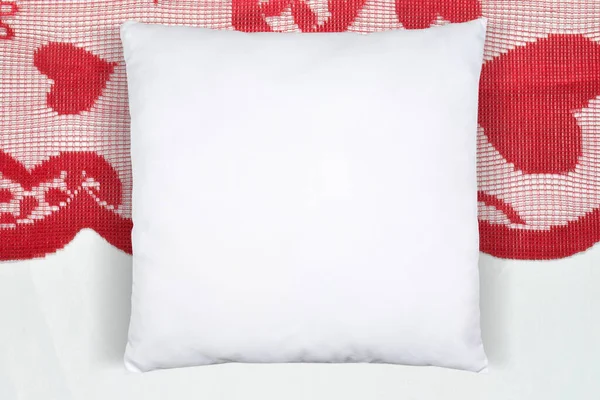 Square white throw pillow resting romantically on a Valentines table runner with hearts