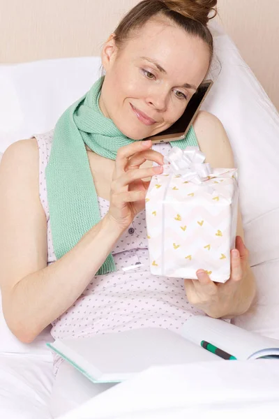 Jovencita enferma con un regalo en su cama — Foto de Stock