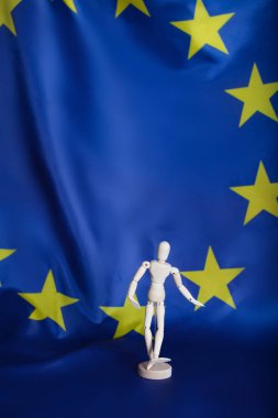 Wooden dummy figurine on European flag. clipart