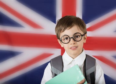 Yedi yaşında boy gülümseyerek bir kitap tutar. Arka plan olarak Büyük Britanya bayrağı. Portre