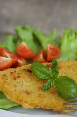 Tavuk şnitzel kiraz domates ve yeşil salata yaprakları. 
