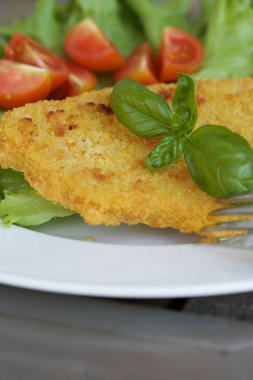 Tavuk şnitzel kiraz domates ve yeşil salata yaprakları. 