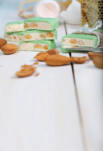 Torrone di mandorle ricoperto di cioccolato al pistacchio su una superficie di legno — Foto Stock