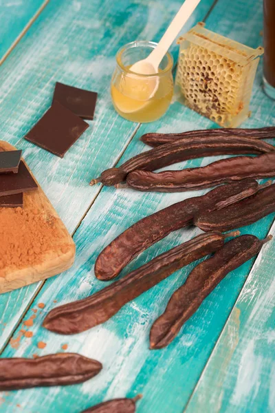 キャロブの莢と木製の表面の粉. — ストック写真