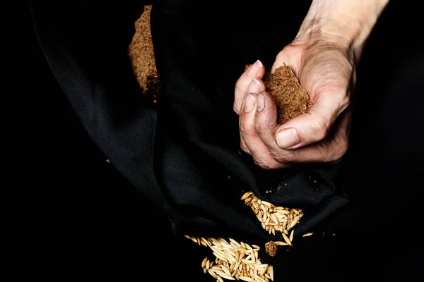 Palma de uma mulher camponesa com pão de centeio em um tecido preto . — Fotografia de Stock