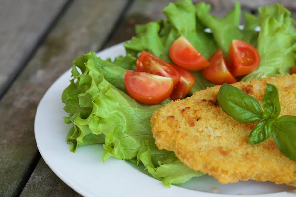 Chicken schnitzel with cherry tomatoes and green salad leaves. Royalty Free Stock Photos