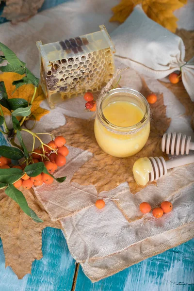 Rowan baies, verre avec miel et nid d'abeille sur un sac . . — Photo