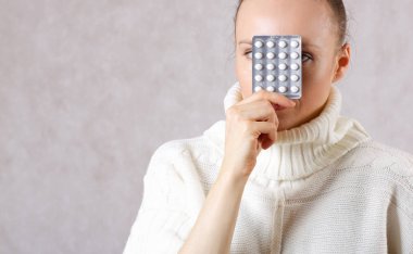 Young caucasian lady between 30 and 40 years old dressed in a knitted sweater with medication. Closeup clipart