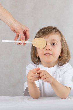 Göz doktoru çocuğun gözleri göz pad ile kapatır. 