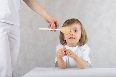 Ophthalmologist closes boy's eyes with eye pad.  clipart