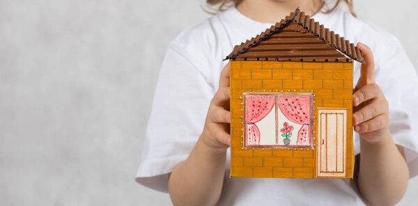 Boy of five years is keeping handmade carton paper house. Closeup