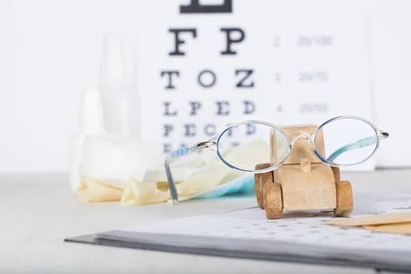 Gafas graduadas para niños en una carta ocular cerca de las almohadillas oculares . — Foto de Stock