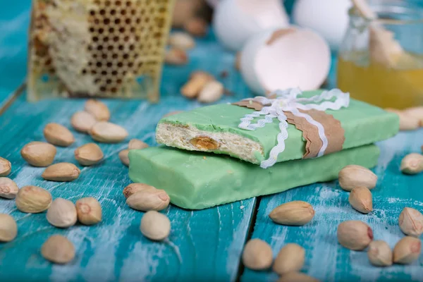 Torrone di mandorle ricoperto di cioccolato al pistacchio su una superficie di legno — Foto Stock