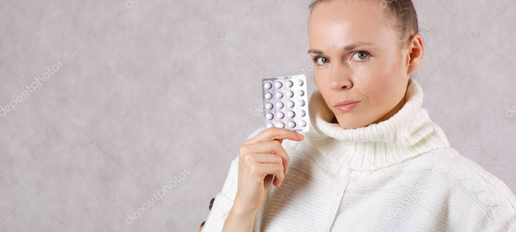 Young caucasian lady between 30 and 40 years old dressed in a knitted sweater with medication. Closeup