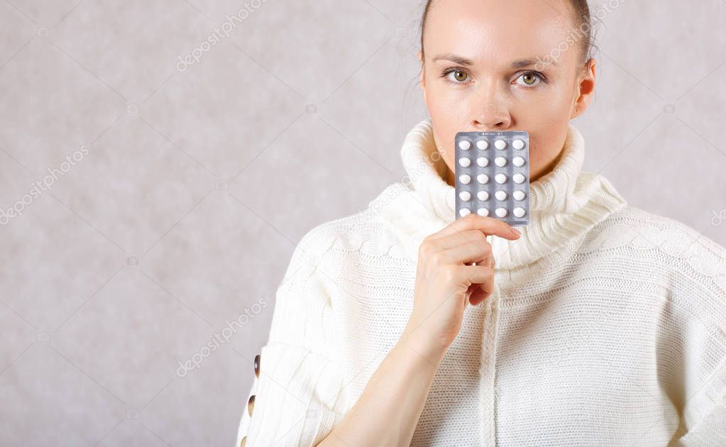 Young caucasian lady between 30 and 40 years old dressed in a knitted sweater with medication. Closeup