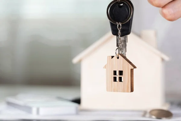 Femme garde la clé de la maison sur un porte-clés en face d'un bois poreux — Photo