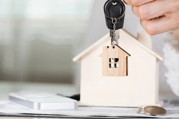 Femme garde la clé de la maison sur un porte-clés en face d'un bois poreux — Photo