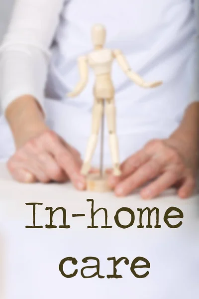 Word IN-HOME CARE. Wooden figurine in the hands of an old woman — 图库照片