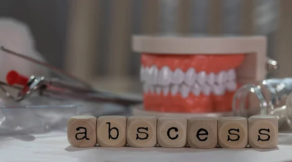 Slovo absces složené z dřevěných kostek. Prášky, dokumenty, pero, hu — Stock fotografie