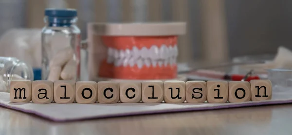 Word MALOCCLUSION composed of wooden dices. Pills, documents, pe — Stock Photo, Image