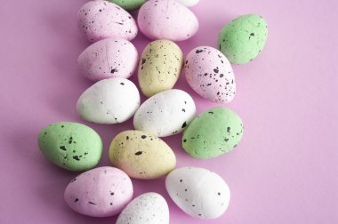 Paskalya arkaplanı, pembe arka planda renkli yumurtalar, tebrik kartı dekorasyonu. Pastel renkler..
