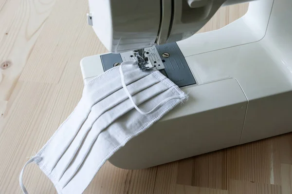El yapımı maske, evde dikiş, yakın çekim, dikiş makinesi. Koronavirüse karşı koruyucu giysiler.